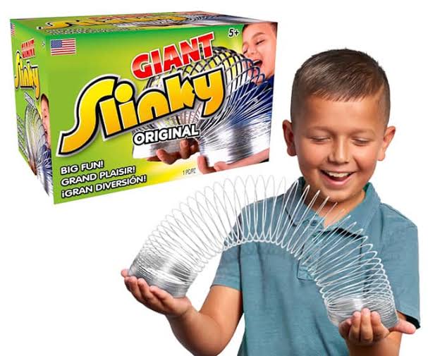 A child happily holding a Slinky Brand Original Giant Slinky Walking Spring Toy next to its retail box